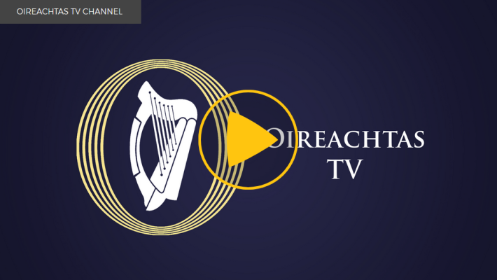 A screenshot of the Oireachteas TV logo, a white harp in a yellow circle.