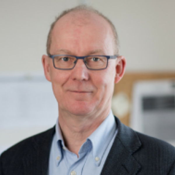 White man with glasses in a navy jacket and blue shirt