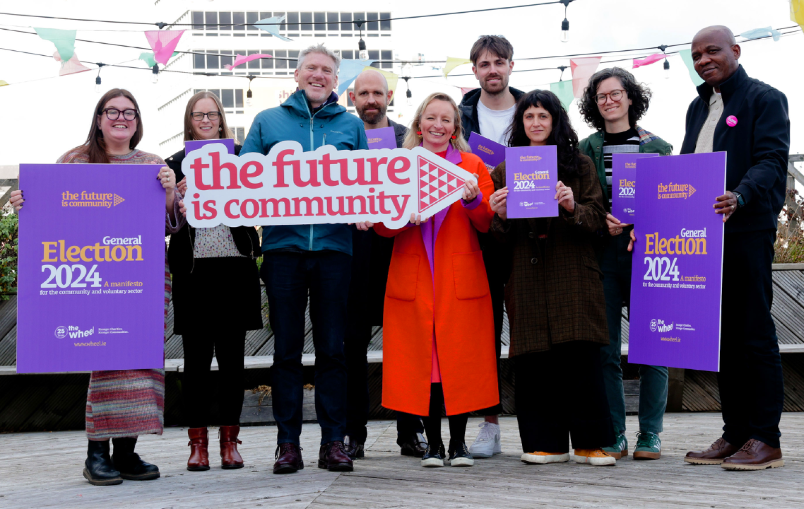 A group shot of representatives of The Wheel staff and We Act steering committee gathered on the roof of the Tara Buildings in Dublin holding banners for The Wheel's General Election 2024 Manifesto